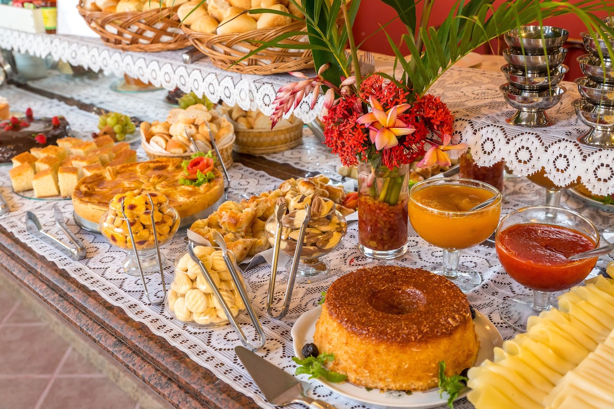 Mesa de café da manhã do Porto Geraes com pães, bolos, frutas e sucos