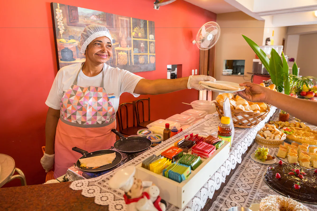 Mesa de café da manhã do Porto Geraes com pães, bolos, frutas e sucos
