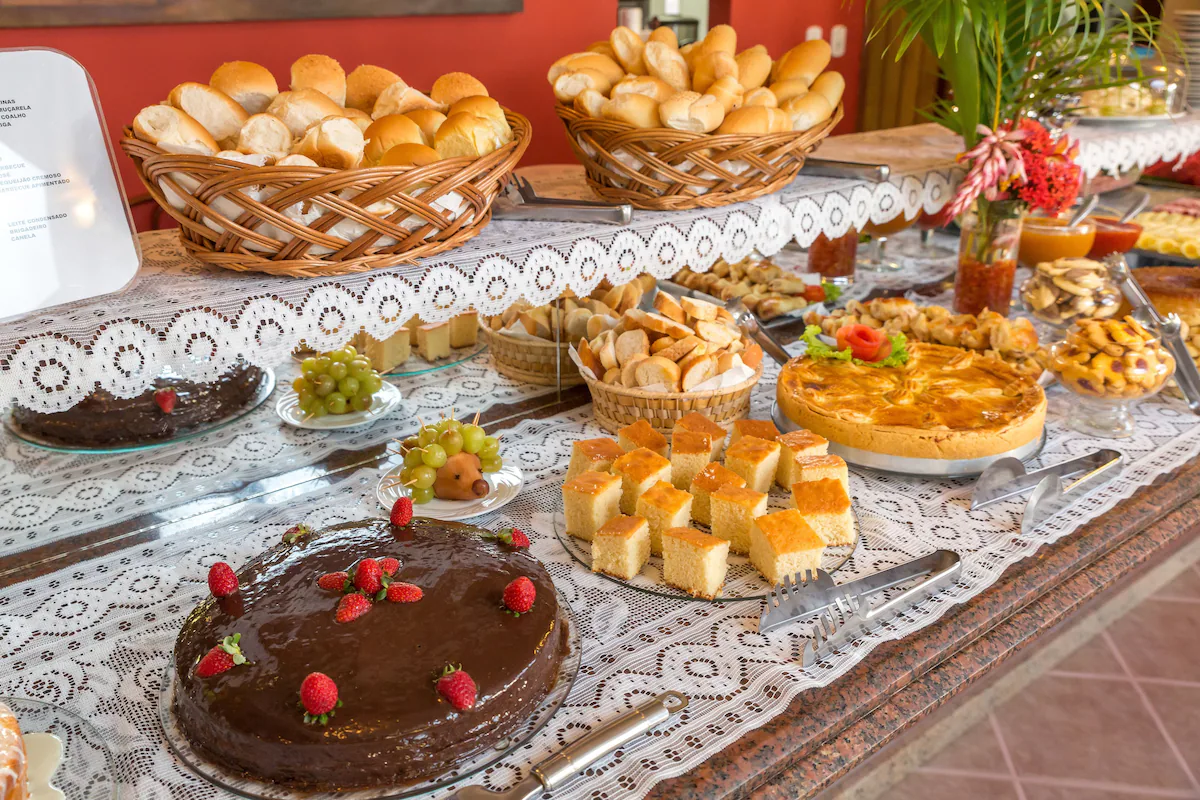 Mesa de café da manhã do Porto Geraes com pães, bolos, frutas e sucos