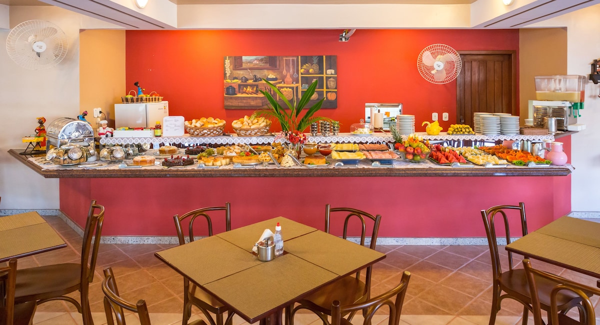 Mesa de café da manhã do Porto Geraes com pães, bolos, frutas e sucos